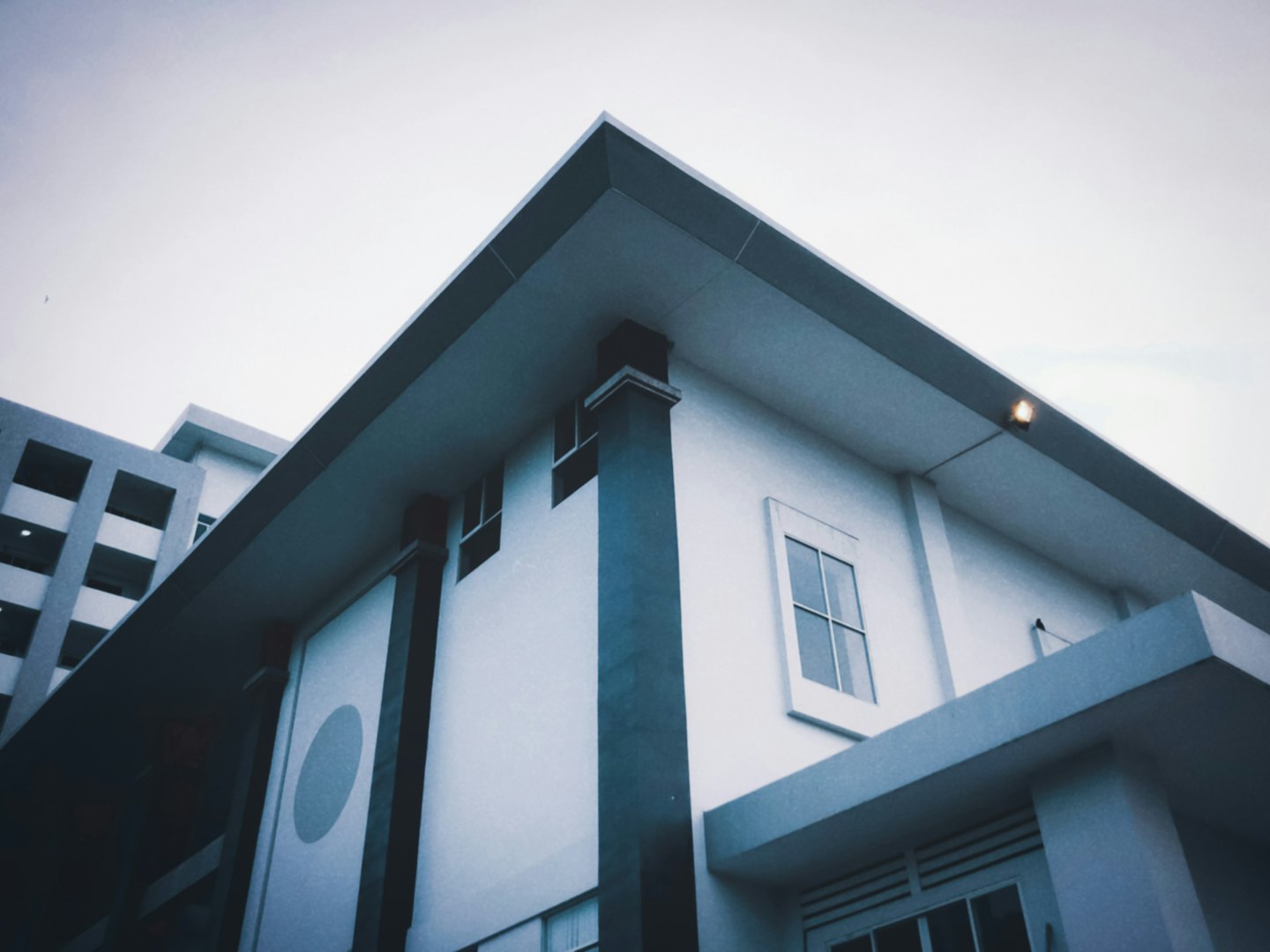 Bâtiment blanc moderne aux lignes géométriques sur fond de ciel dégagé.