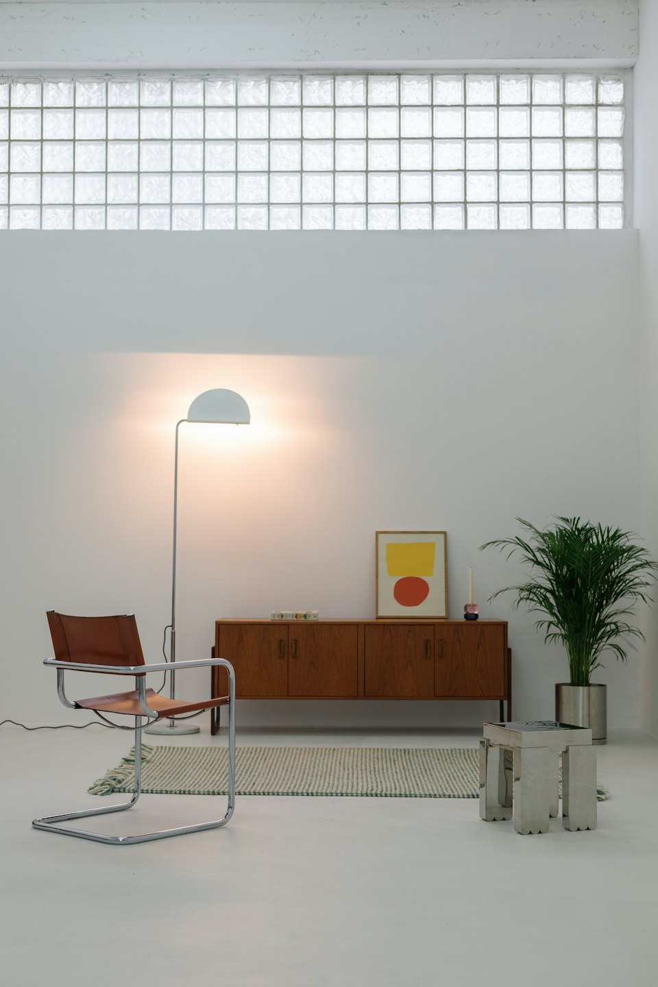 Chambre minimaliste moderne avec fauteuil en cuir et plante d'intérieur.